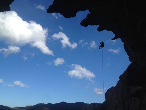 Un grimpeur remonte sur une corde pour accéder au sommet de la falaise. Événement Team Building Escalade